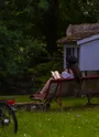 Image d'illustration du parcours "Patrimoine et culture" | jeune femme lisant un livre sur un banc au bord d'un ruisseau